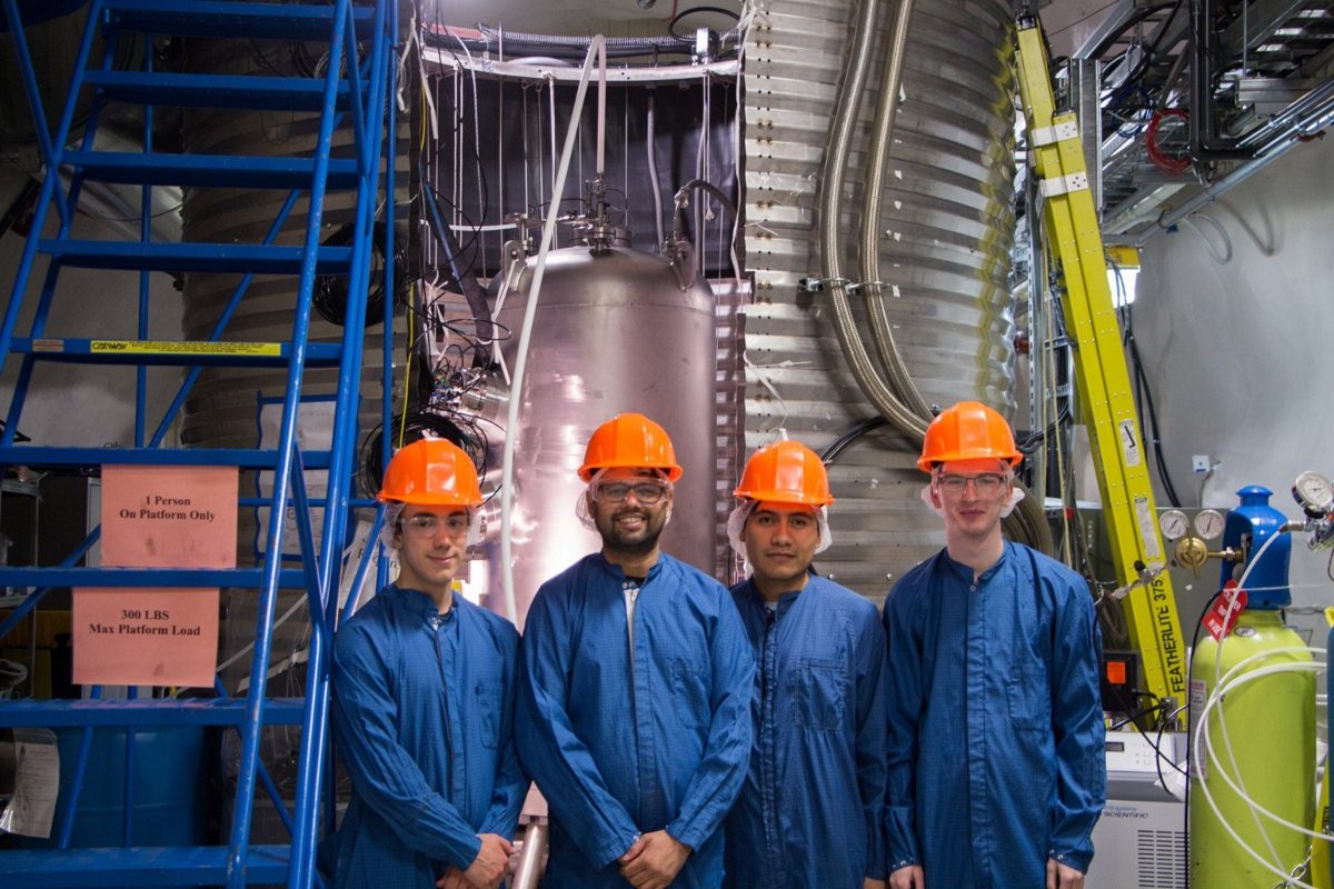 Group of researchers in blue coveralls and orange hard hats